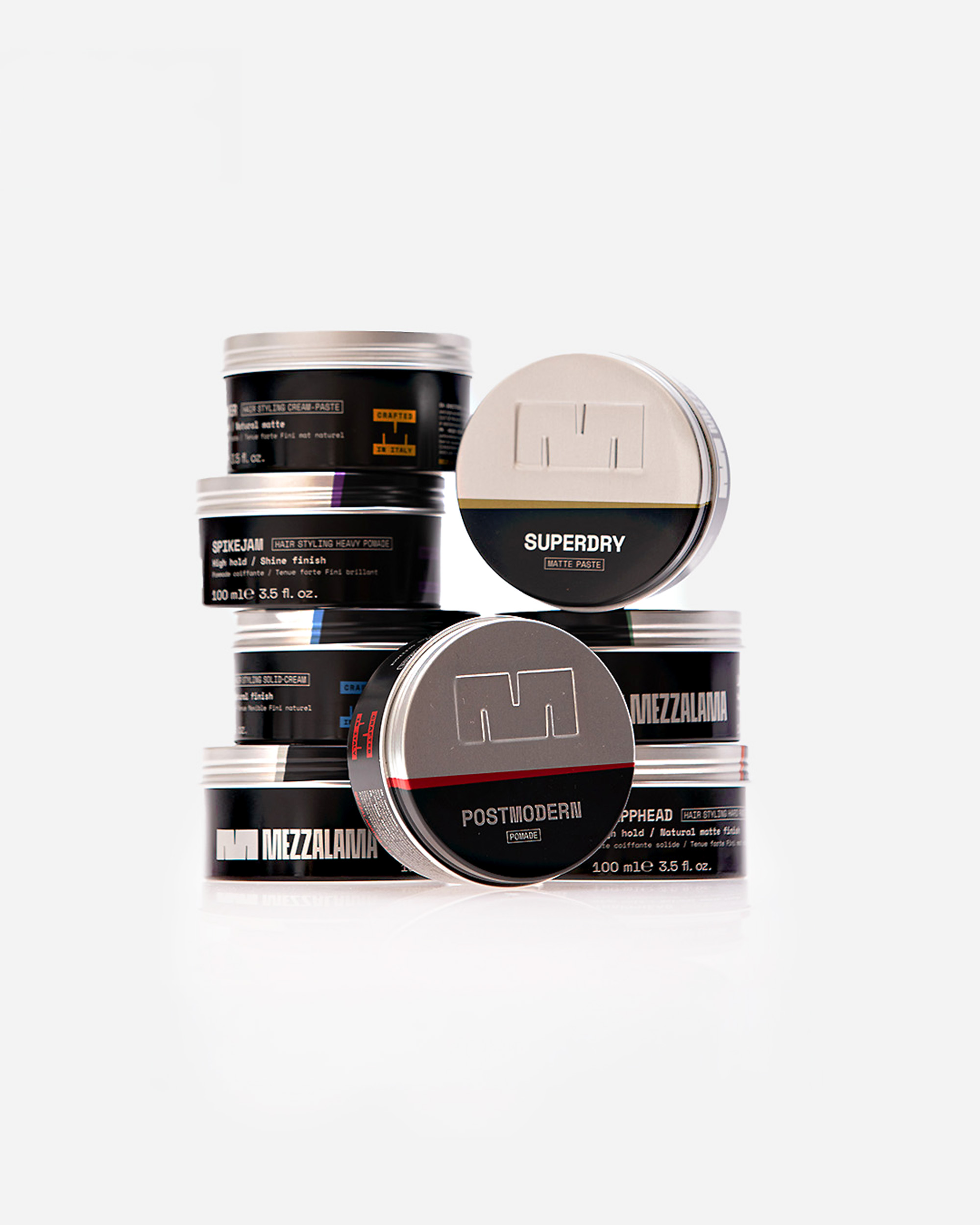 Stacked Mezzalama wax and pomade tins with the embossed M lid